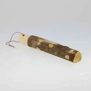 Schräge Aufsicht auf einen liegenden japanischen Holzstößel mit natürlicher Rinde, hellen Holzpunkten und einer Kordelschlaufe am glatt geschliffenen Ende.