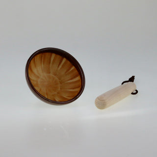 Schräge Aufsicht auf einen kleinen braunen Keramik-Mörser mit gerillter Innenseite, daneben liegt ein heller Holzstößel mit Kordel.