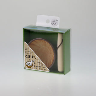 Schräge Aufsicht auf die grüne Originalverpackung des Mörser-Sets mit transparentem Fenster, das den braunen Keramik-Mörser und den Holzstößel im Inneren zeigt.