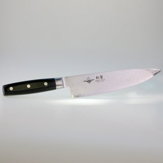 Seitenansicht des japanischen Santoku-Kochmessers Hideyoshi mit dunklem Griff und einer Klinge aus Damaststahl, auf der feine Wellenmuster und japanische Schriftzeichen zu sehen sind.
