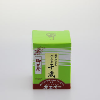 Eine leuchtend grüne Matcha-Packung mit der Bezeichnung "Chitose". Auf der oberen linken Seite der Packung befindet sich eine Zeichnung eines traditionellen japanischen Schreins. Die Verpackung enthält japanische Schriftzeichen und hat eine braunrote Basis. Der Hintergrund ist schlicht und weiß gehalten.