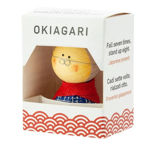 Okiagari-Figur einer Großmutter in einer dekorativen Geschenkbox mit der Aufschrift „OKIAGARI“ und dem japanischen Sprichwort „Fall seven times, stand up eight“.