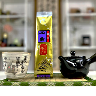 Links im Bild steht unsere Teetasse "Jizo", daneben eine goldene Packung Gyokuro Soshou, rechts steht eine schwarze Kyusu-Teekanne. 