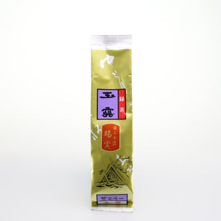 Eine längliche Packung Gyokuro Yashiro. Die Packung ist goldfarben. Darauf befinden sich Etiketten in den Farben Rot, Lila und Orange, mit japanischer Schrift. Unten auf der Packung sieht man eine Zeichnung von einem japanischen Schrein.