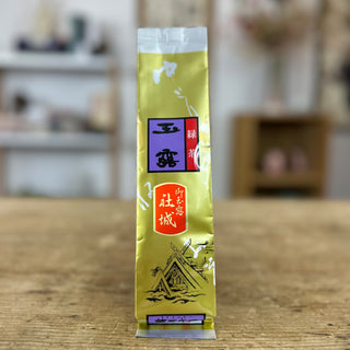 Eine goldene Packung Gyokuro Yashiro steht auf einer hellen Holzplatte.