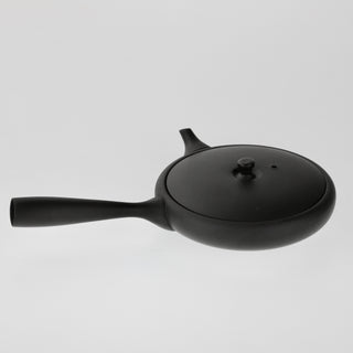 Schräge Aufsicht auf die schwarze Teekanne Hiragata Kyusu Shizuku mit geschlossenem Deckel, Stielgriff und kurzem Ausguss.