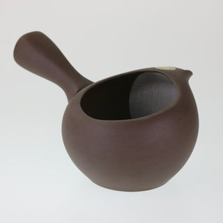 Schräge Aufsicht auf die deckellose, dunkelbraune Teekanne Kyusu Kashi mit seitlichem Griff, die den Blick in das Innere mit dem integrierten Sieb freigibt.