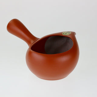 Schräge Aufsicht auf die orangefarbene Teekanne Kyusu Kinkan mit seitlichem Griff, die den Blick in das Innere mit dem flachen Korbsieb freigibt.