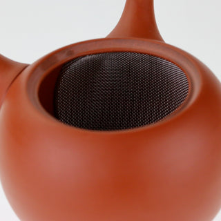 Detailaufnahme der geöffneten rotbraunen Teekanne Kyusu Renga, die das Innere mit dem integrierten Sieb zeigt.