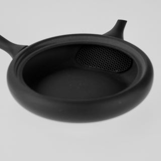 Detailaufnahme der geöffneten schwarzen Teekanne Hiragata Kyusu Shizuku, die das Innere mit integriertem Sieb vor dem Ausguss zeigt.