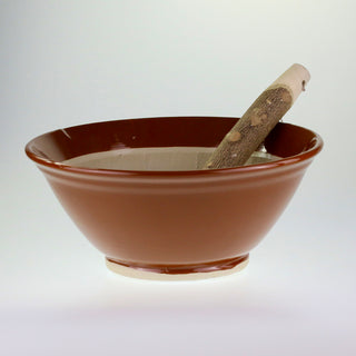 Schräge Aufsicht auf den braunen japanischen Keramik-Mörser Suribachi mit einem hölzernen Stößel im Inneren.