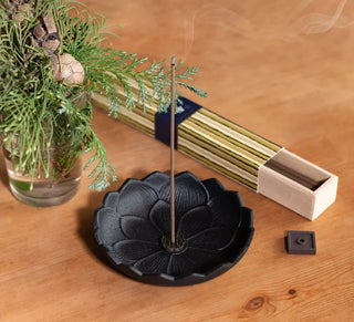 Schwarzes Räuchergefäß Lotus mit brennendem Räucherstäbchen auf Holztisch