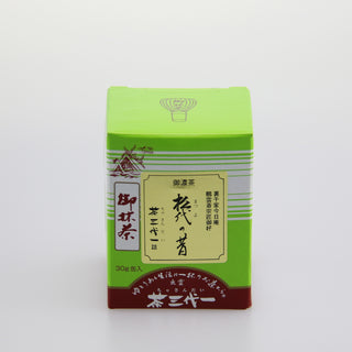 Eine leuchtend grüne Packung Matcha mit der Bezeichnung "Matsuyo no Mukashi". Auf der oberen linken Seite befindet sich eine Zeichnung eines traditionellen japanischen Schreins. Die Packung ist mit japanischen Schriftzeichen versehen und hat einen braunroten unteren Bereich. Der Hintergrund ist schlicht und weiß.