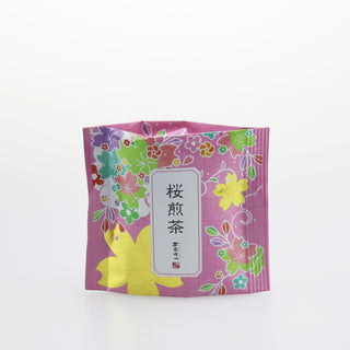 Eine rosarote Verpackung, verziert mit gelben, grünen, roten, violetten und rosaroten Blüten. In der Mitte ist ein Etikett mit japanischen Schriftzeichen angebracht. In der Packung befindet sich Sakura Sencha