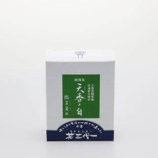 Eine weiße Packung "Tenko no Shiro"-Matcha. Darauf befindet sich ein grünes Quadrat mit weißen Schriftzeichen. Der untere Rand ist dunkelblau gehalten, ebenfalls mit japanischen Schriftzeichen.