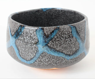 Handgefertigte Matcha-Schale Aokage mit grauschwarzer Oberfläche und leuchtend blauen Glasurverläufen auf der Außenseite.