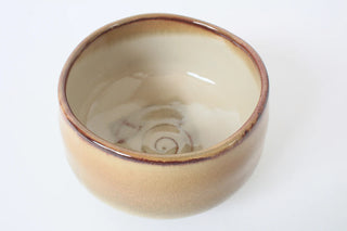 Innenansicht der Chawan Kogashi mit cremig heller Glasur, braunem Rand und feinem Spiraldetail am Boden.