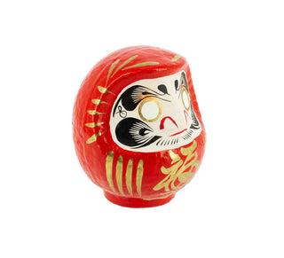 Seitliche Ansicht einer roten Daruma-Figur aus Papiermaché mit traditionellem japanischem Gesichtsmotiv