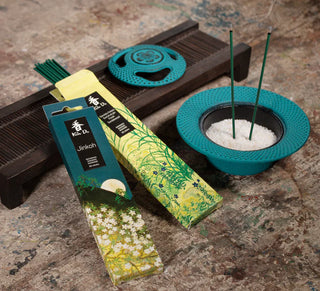 Koh-Do Räucherstäbchen Sandelholz & Kiefer neben Räucherstäbchenhalter mit brennendem Duftstäbchen, stimmungsvolles Arrangement